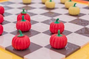 Cerca del tablero de ajedrez con damas de calabaza, fondo de colores foto