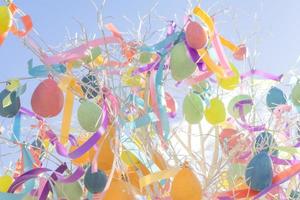 huevos de pascua multicolores brillantes con cintas cuelgan en el árbol. fondo festivo de pascua foto
