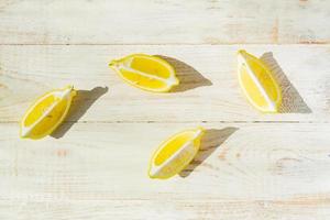 top view of  quarter lemons scattered on wooden table. Hard shadows in a saunny day photo
