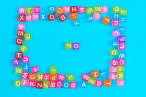 NO inscription made of colorful cube beads with letters. Festive blue background concept with copy space photo