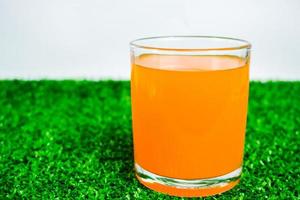glass of orange juice on a green background photo