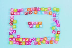 Keep calm inscription made of colorful cube beads with letters. Festive blue background concept with copy space photo