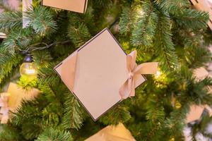 fondo de vacaciones de navidad y año nuevo. árbol de navidad con guirnalda y caja de regalo con lazo foto