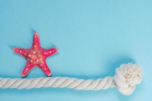 Red starfish and knot rope on light blue background with copy space. summer holiday and vacation concept photo