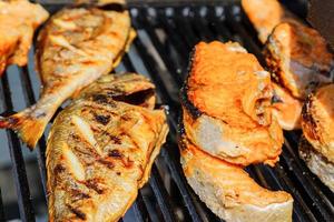 close up of tasty roasted salmon and perch on grill outdoors. Street food. photo