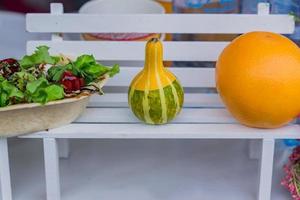 rural market decoration. Small pumpkin, orange and salad on white wooden bench photo