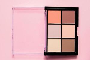 paleta de sombras de ojos en tonos marrones y morados sobre fondo rosa foto