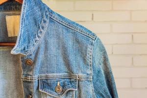 chaqueta de mujer de mezclilla azul en una percha de madera. ropa de moda. foto