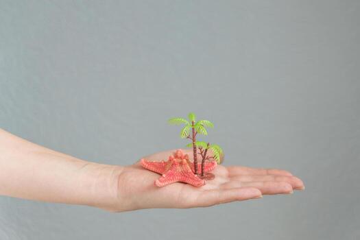 estrella de mar y palmera en mano de mujer. concepto de viajes y vacaciones. foto