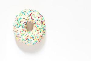 White frosted donut with colorful sprinkles  on white background. photo