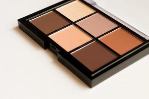 Natural look, Brown tone eye shadows make up palette in black case on white background. Selective focus photo