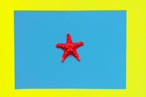 estrella de mar roja sobre fondo azul claro y amarillo con espacio de copia. concepto de vacaciones y vacaciones de verano foto