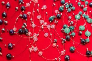 Colorful crystal beads necklaces on red background. Background pattern. Handicraft fashionable for women photo