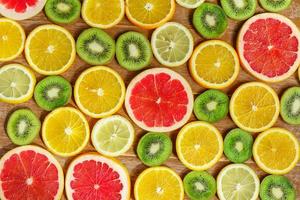 frame with slice of oranges, lemons, kiwi, grapefruit pattern isolated on wooden background. Flat lay, top view photo