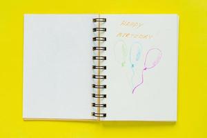 vista superior del cuaderno con saludo de feliz cumpleaños y tres globos dibujados con espacio de copia. concepto de celebración foto