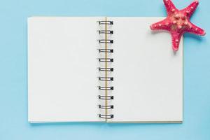 Top view of open empty notebook with red starfish on pastel blue colorful background. Travel and holiday concept photo
