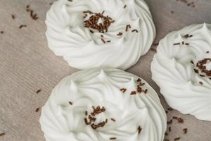 homemade white air meringues and chocolate confectionery decorations on  on parchment paper. photo