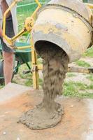 trabajador de la construcción saca hormigón de la hormigonera. proceso de creación de cemento en el sitio de construcción foto