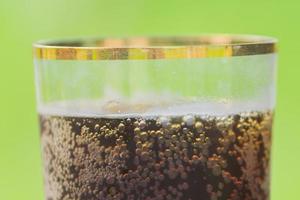 close up of glass of rye kvas on green background. Traditional russian drink with bubbles photo