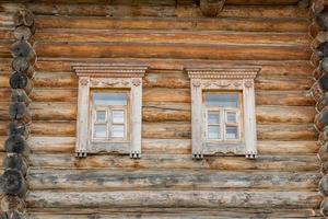 close up of wooden log house. two windows on the wall photo