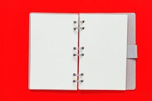libreta de espiral limpia para notas y mensajes sobre fondo rojo. plano de negocios mínimo foto