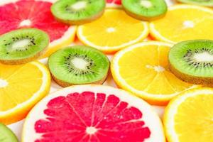 close up of citrus slice, kiwi, oranges and grapefruits isolated on white background. Fruits backdrop, selective focus photo