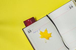 Black friday sale concept. Shopping list in notebook and bank card as bookmark on yellow backgrond photo