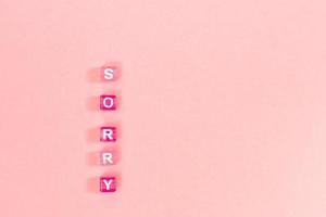 sorry  inscription made of colorful cube beads with letters. Festive pink background concept with copy space photo