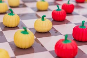 Cerca del tablero de ajedrez con damas de calabaza, fondo de colores foto