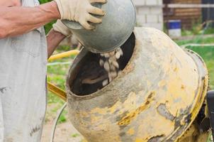 trabajador de la construcción hace hormigón en hormigonera giratoria. proceso de creación de cemento en el sitio de construcción foto