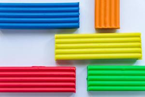 Set of multicolored plasticine bars for modelimg on white background. photo