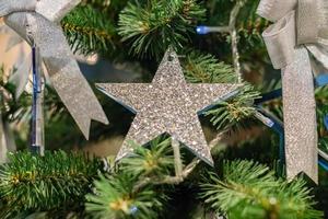 fondo de vacaciones de navidad y año nuevo. árbol de navidad decorado con lazo plateado y estrella azul. concepto de celebración foto