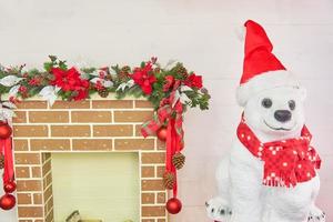 oso polar con chimenea navideña decorada con bolas y lazos. interior de la sala de navidad. foto