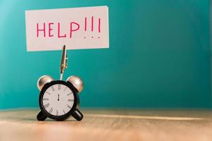 Alarm clock and banner with handwritten phrase help on wooden table. Time management concept. photo