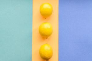 three lemons on colorful orange, blue and green background, top view, minimal flat lay. photo