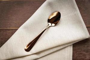 Close up of textile beige napkin and served tea spoon on wooden table. photo