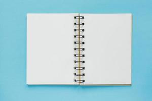 vista superior del cuaderno vacío abierto con tapa de papel reciclado sobre fondo de color azul pastel foto