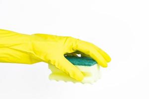 mano con guante amarillo sosteniendo una esponja verde para limpiar sobre fondo blanco foto