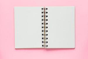 Clean spiral note book for notes and messages on pastel pink background. Minimal business flat lay photo