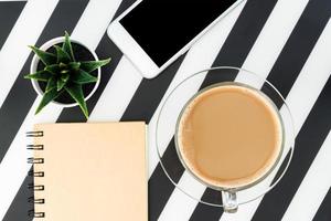 Black and White office desk table with blank notebook, smartphone, cup of coffee and supplies. Top view with copy space, flat lay. photo