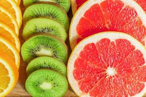 frame with slice of oranges, lemons, kiwi, grapefruit pattern on wooden background. copy space. photo