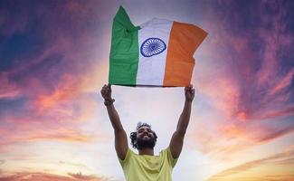 joven ondeando la bandera nacional india sobre el hermoso fondo del cielo foto