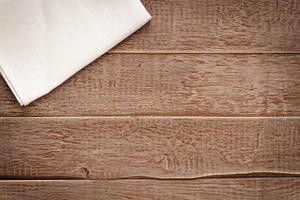 Top view of cloth napkin of beige  coloron rustic wooden background. photo