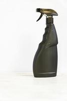 Black blank plastic spray detergent bottle on white background. Household chemicals. Cleaning product. photo