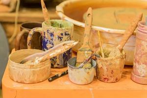 close up of dirty pottery wheel and colorful mud in jars after work photo