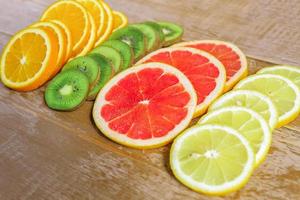 frame with slice of oranges, lemons, kiwi, grapefruit pattern on wooden background. copy space. photo