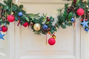 hermosa guirnalda navideña decorada con ramas de árboles de piel. bolas y conos multicolores. decoración interior de vacaciones foto