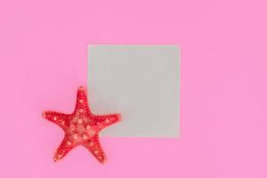 Red starfish on light pink background with copy space. summer holiday and vacation concept photo