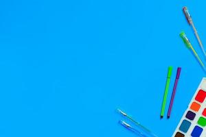 stationery accessories - pens, markers, paints on blue background. Composition mock-up, Back to school concept with office supplies. Top view photo