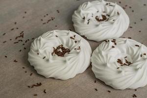 homemade white air meringues and confectionery decorations on  on parchment paper. photo